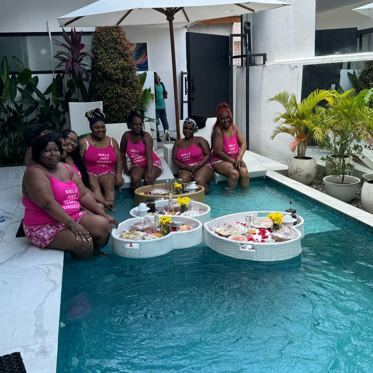 a group of female with pink clothes by the pool enjoying floating breakfast