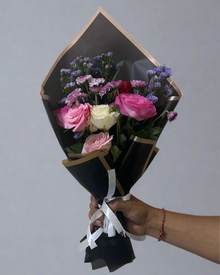 small flower bouquet with black paper contains pink and white roses