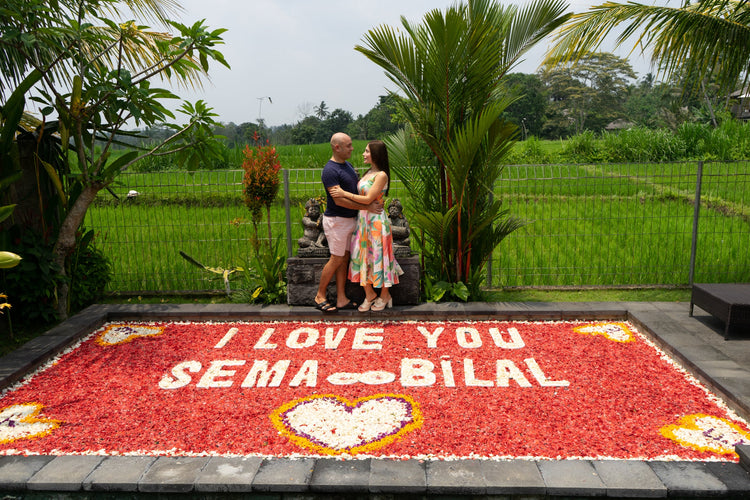 a couple posing in front of pool decorated with flower petals celebrating honeymoon in Bali