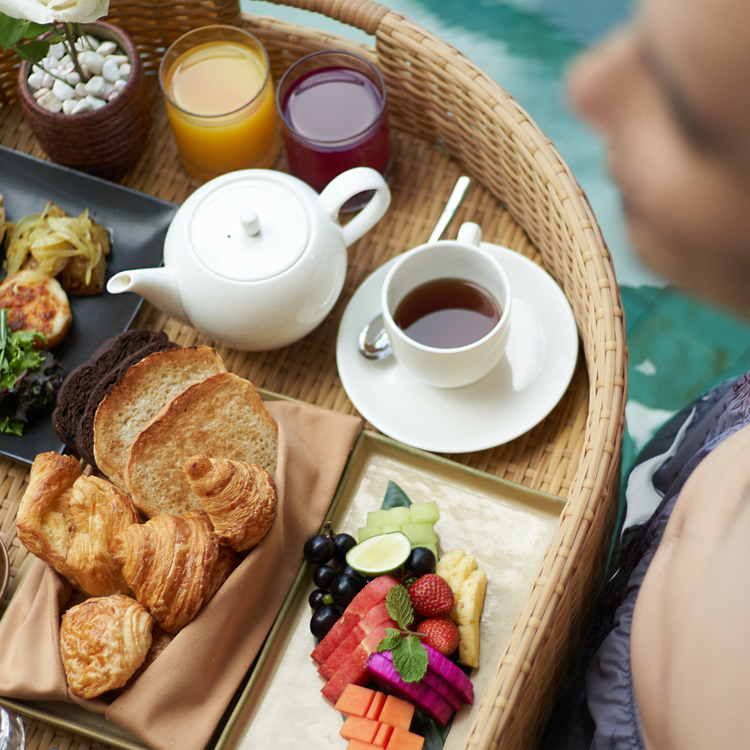 man sitting by the pool having a floating breakfast top view