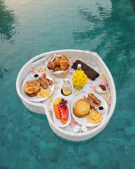 Floating breakfast tray with food items on a pool
