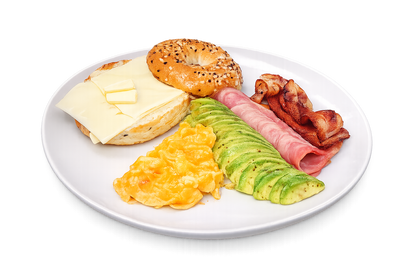 Breakfast plate with bagel, cheese, eggs, avocado, ham, and bacon on a white background