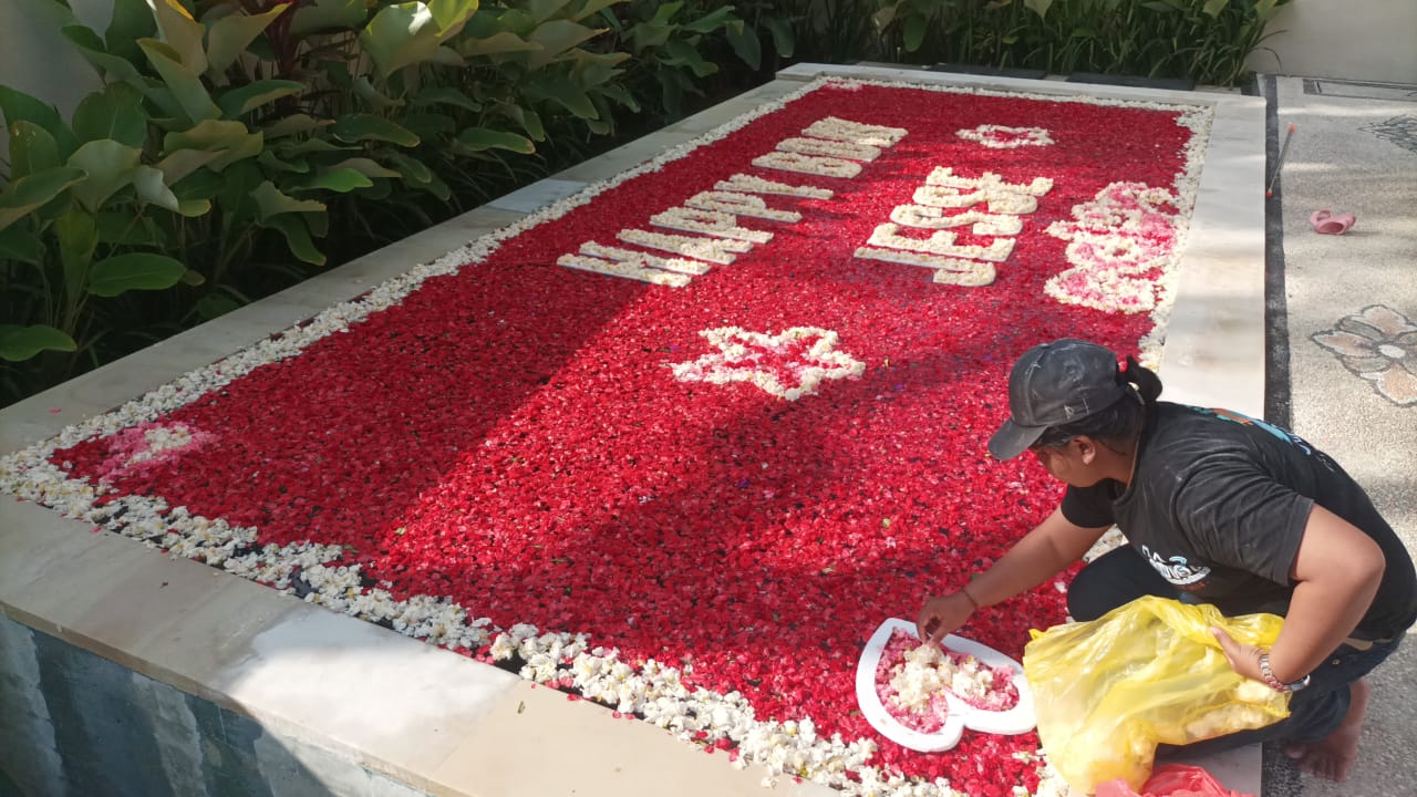 a worker decorating bali villa pool with flower petals for birthday celebration